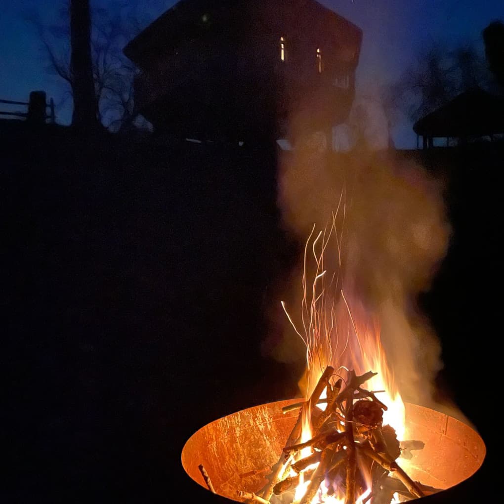 Lit fire pit at night with Eathelin's silhouette