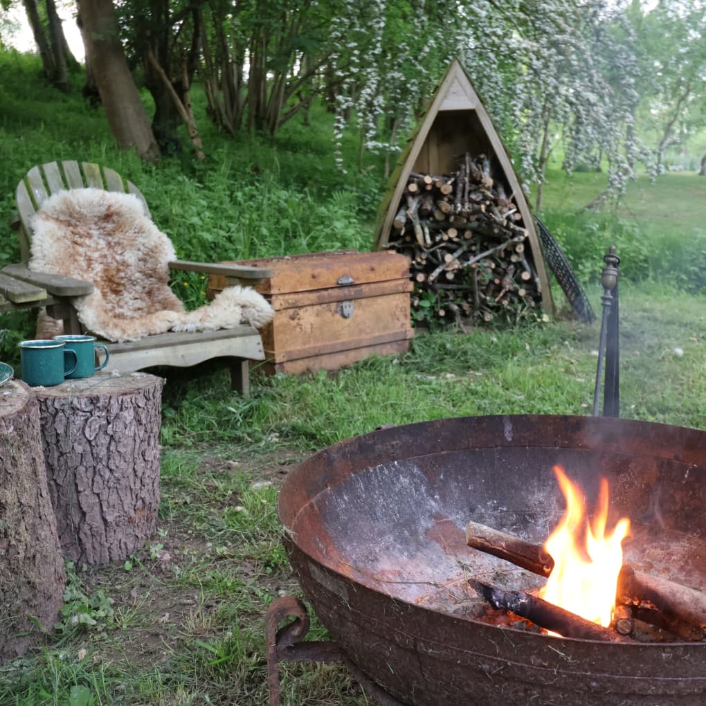 Lit fire pit with outdoor seating area and wood store