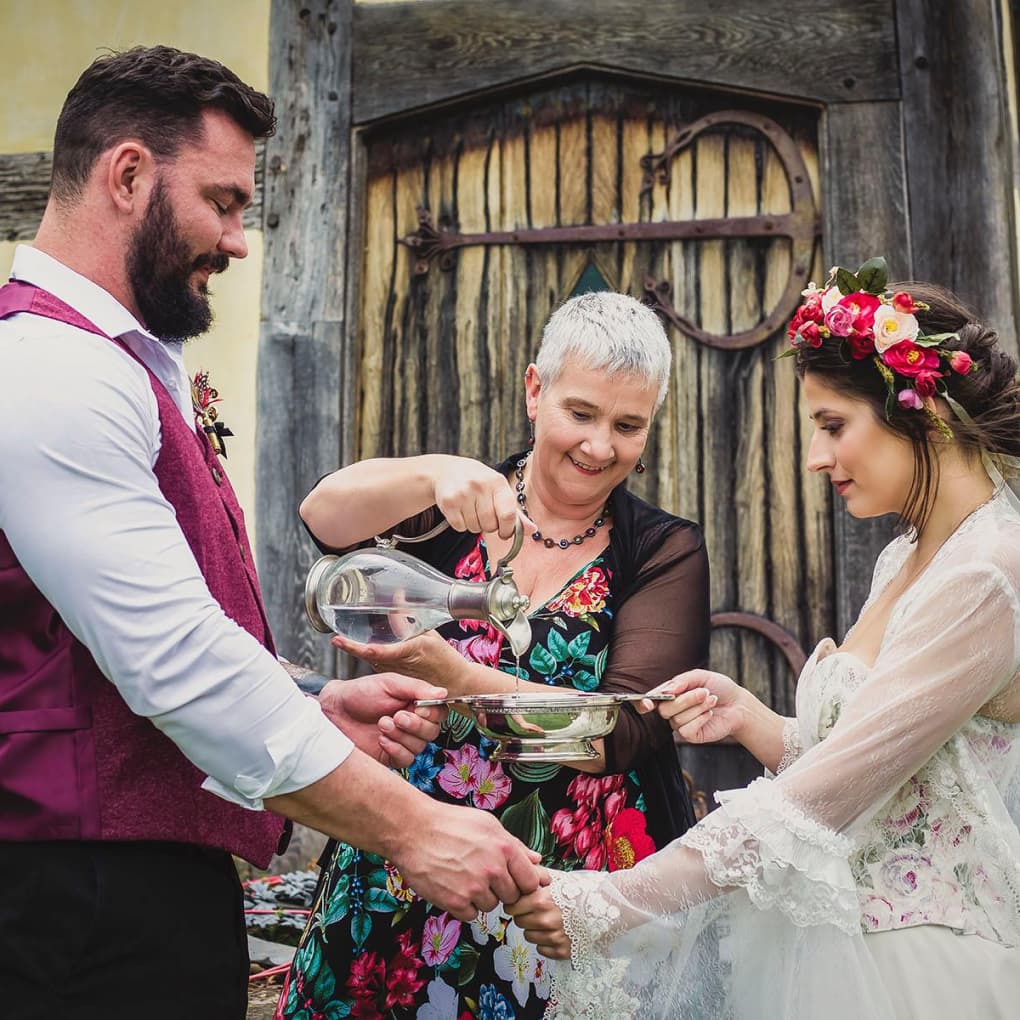 A woman officiating a ceremony between a man and a woman